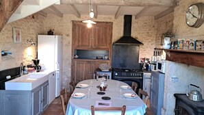 Una cocina rústica con una mesa de comedor para cuatro personas, estufa y armarios de madera.