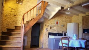 Una cocina rústica con una escalera de madera, un lavamanos y una mesa de comedor para dos.