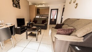 A modern living room with a sofa, coffee table, TV, and dining area. - 60sq.m Roof Solarium, 50sq.m Rear Terrace: BBQ, Fibre WiFi, TV (BBC, SKY sports) (Corralejo)