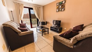 A living room with two sofas, a coffee table, a TV, and a dining table with chairs. - 60sq.m Roof Solarium, 50sq.m Rear Terrace: BBQ, Fibre WiFi, TV (BBC, SKY sports) (Corralejo)