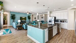 A spacious kitchen with a central island, white cabinetry, and a teal accent wall. - South View Luxury 5★ Villa: Pool, Spa, Game Room, Near Disney & Universal (Davenport)
