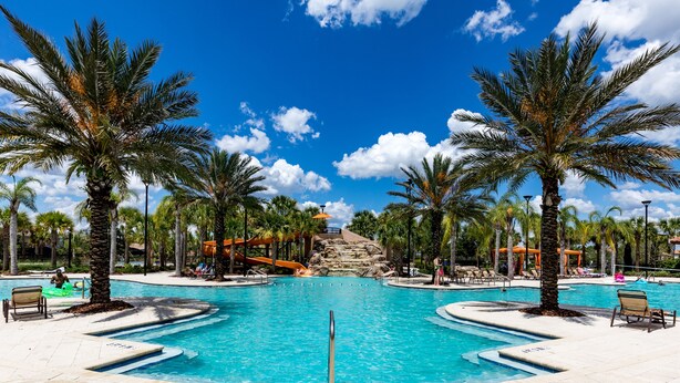 A large outdoor swimming pool surrounded by palm trees and lounge chairs. - South View Luxury 5★ Villa: Pool, Spa, Game Room, Near Disney & Universal (Davenport)