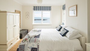 A bedroom with a bed, a wardrobe, a window with a view, and a radiator. - Light filled home from home with spectacular panoramic sea views of Mounts Bay (Mousehole)