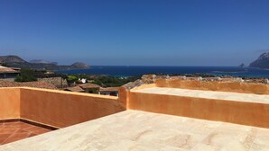 A rooftop terrace with a view of the sea and distant mountains.