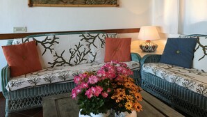 A living room with a sofa, cushions, a lamp, and a wall painting.