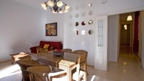 A dining area with a wooden table and chairs, a chandelier, and wall-mounted mirrors. - Beautiful apartment in  historical recently reformed building. (Sevilla)