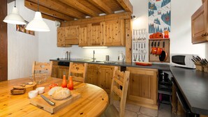Eine Holz-Küche mit Esstisch, Stühlen und diversen Küchengeräten.