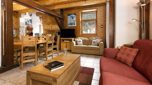 Ein Holzinterieur mit Essbereich, einer Couch und einem Fernseher.