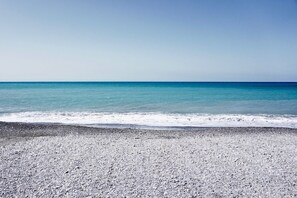 A beach with a pebbly shore and calm sea.