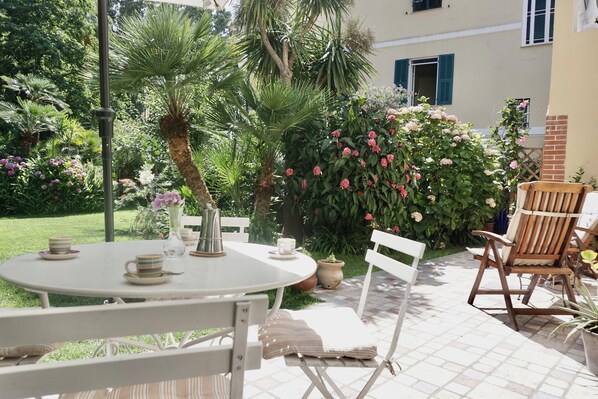 An outdoor patio with a round table, chairs, and a potted plant.