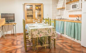 A dining area with a table set for four, a wooden cabinet with glass doors, a television on a stand, and a kitchen area with a microwave and sink. - Stone house n��3 for 4 people, Batan Rio Tus (Yeste)