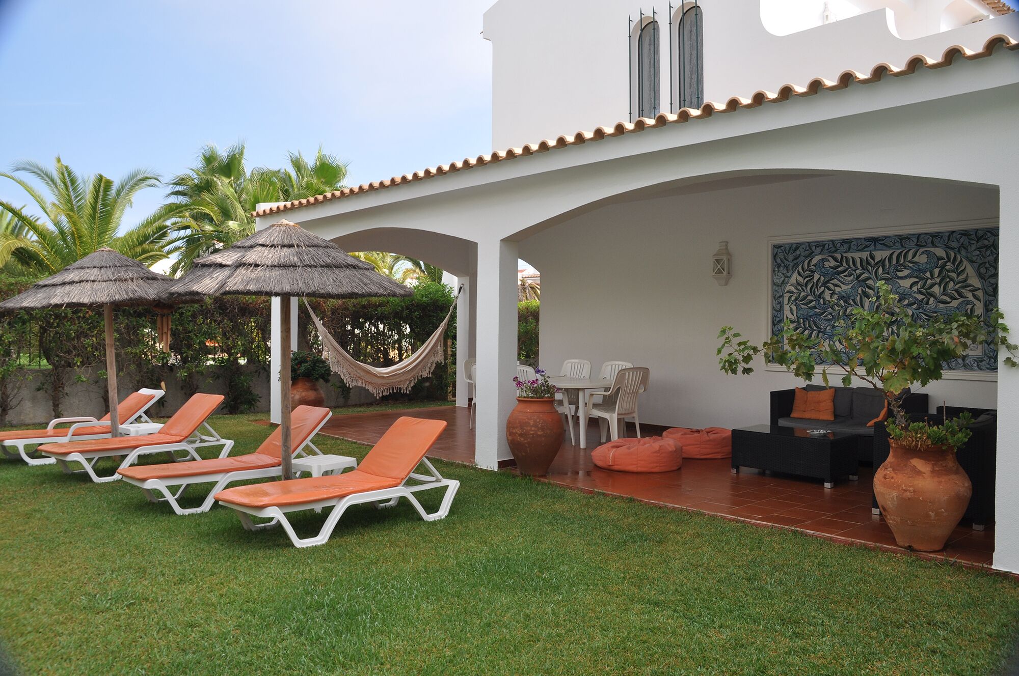A covered outdoor area with lounge chairs, a hammock, and a dining set.
