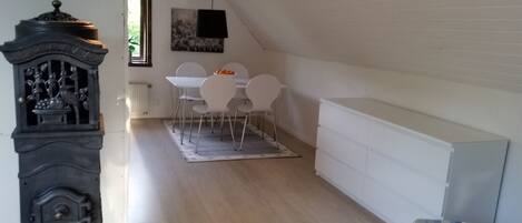 A dining area with a table and chairs, a radiator, a clock, and a white cabinet.