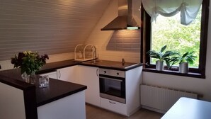 Una cucina compatta con finestra, mobili bianchi, forno integrato e scolapiatti.