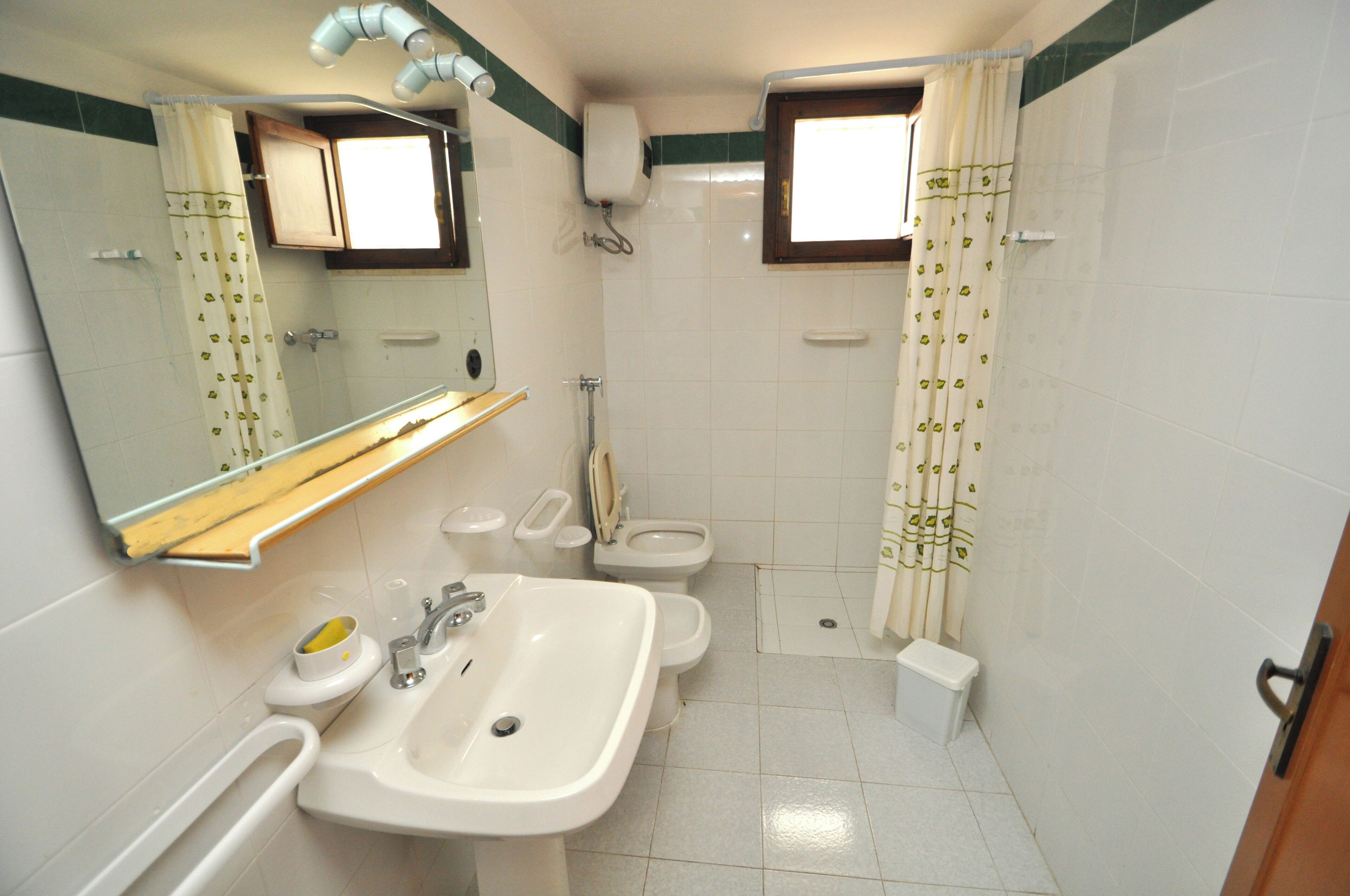 Une salle de bain équipée d’un lavabo, d’un miroir, de toilettes et d’un rideau de douche.