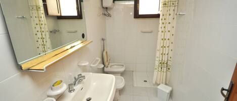 Une salle de bain équipée d’un lavabo, d’un miroir, de toilettes et d’un rideau de douche.