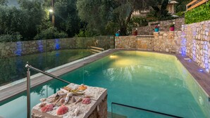 A swimming pool with stone walls and potted plants. - Villa Parga – with private pool and authentic Sunset Panorama view! (parga)