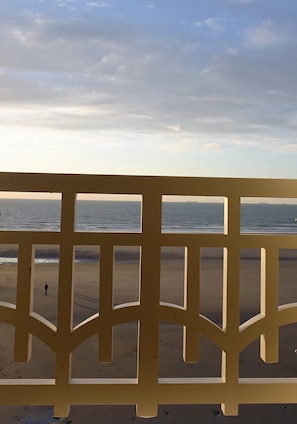 A beach view through a wooden fence with a person walking on the sand. - Splendid sea view, apprt. 50 m² completely renovated! WIRELESS (Wimereux)