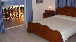 A bedroom with a wooden bed, a nightstand with a lamp, a painting on the wall, and a view of the sea through a window. - Private Villa with superb seaview, swimming pool, garden, parking, pet friendly (Corfu)