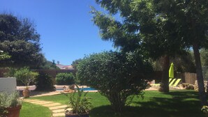 A backyard with a swimming pool, a stone pathway, and various potted plants. - Calm, serene, secluded, stunning gardens, pool close to beach and all amenities  (Binibequer)