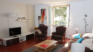 A modern living room with a TV, two armchairs, a sofa, a coffee table, and a bookshelf. - Apartment/ flat - Hyères (Hyères)