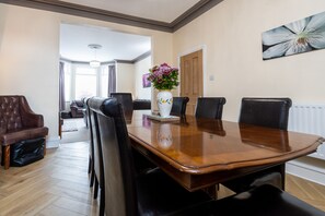 Un coin repas avec une table en bois et des chaises noires, un vase rempli de fleurs et un tableau accroché au mur.