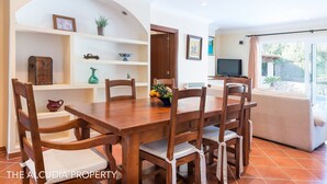 A dining area with a wooden table and chairs, a TV, and a view of the outdoors. - Fabulous family Villa with pool, 500 m from the beach, for 6 people (Alcúdia)