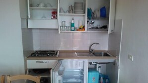 A compact kitchen with a stove, sink, and a refrigerator.