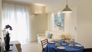 Un coin repas avec une nappe bleue, des assiettes blanches et un tableau accroché au mur.