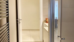 Un couloir avec un radiateur, une porte donnant sur une pièce et une petite table sur laquelle se trouve un bol.