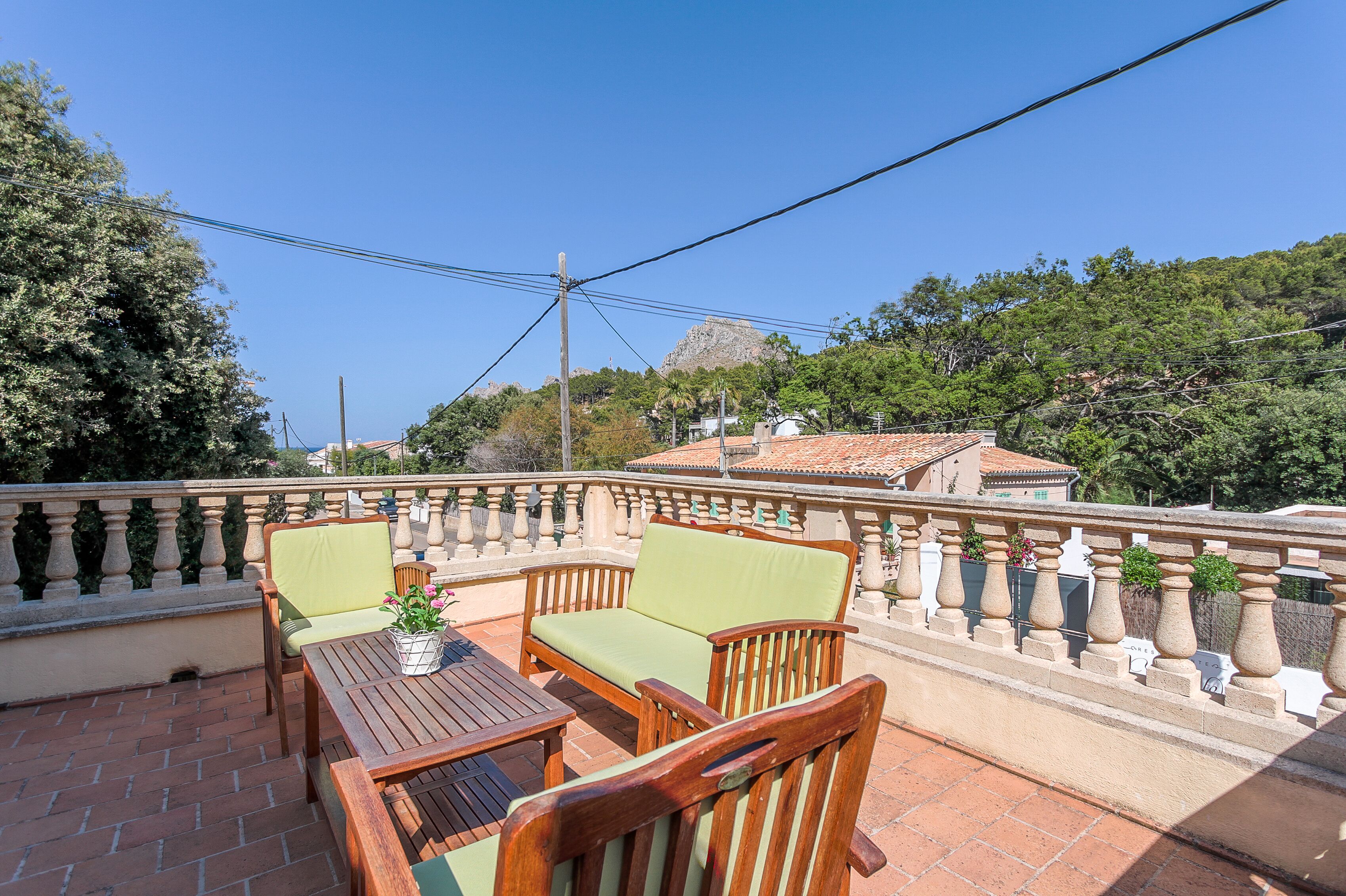 A terrace with wooden furniture and a view of a mountain.