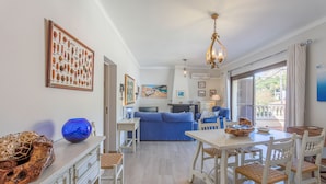 A modern living room with a dining area, a blue sofa, and a framed picture of pottery.