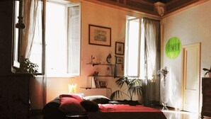 A room with a bed, a desk, a chair, a plant, and a window. - Period residence located in the heart of Siena (Siena)