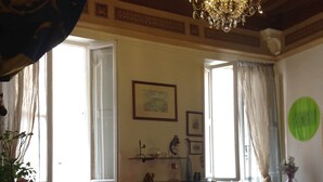 A room with a bed, a chandelier, a window with curtains, and a plant. - Period residence located in the heart of Siena (Siena)