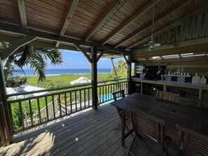Un espace extérieur abrité, doté d’une terrasse en bois, d’une table, de chaises et offrant une vue sur l’océan.