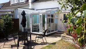 Ein Wintergarten mit Glastür, einem Tisch und zwei Stühlen.