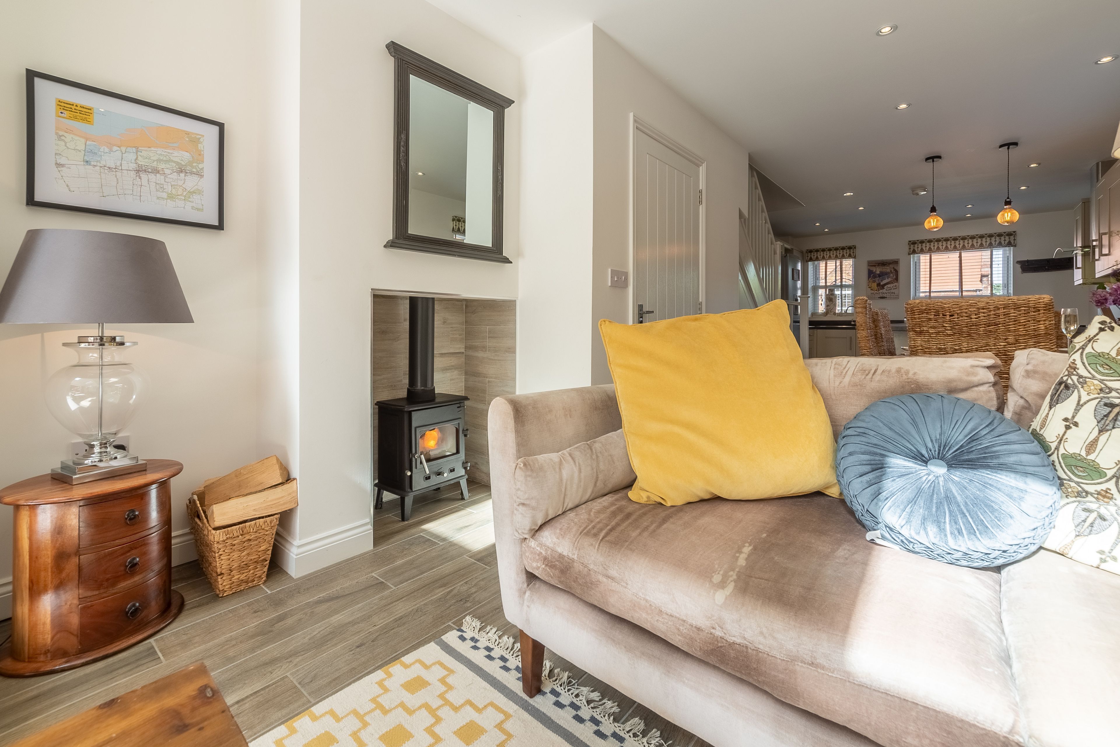 A cozy living room with a sofa, a lamp, a fireplace, and a map on the wall.