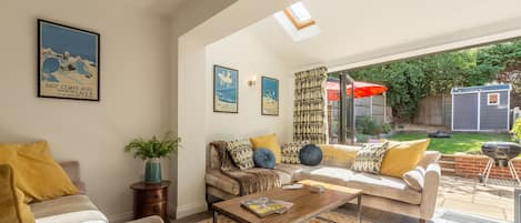 A spacious living room with a sofa set, a coffee table, and a large window.