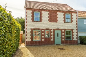 A two-story house with a brick facade and a green door. - Driftwood Cottage, Brancaster, Norfolk (King's Lynn)