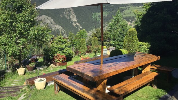 A wooden picnic table with a white umbrella, surrounded by lush greenery and a mountainous backdrop. - Apartment/ flat - Canillo (canillo)