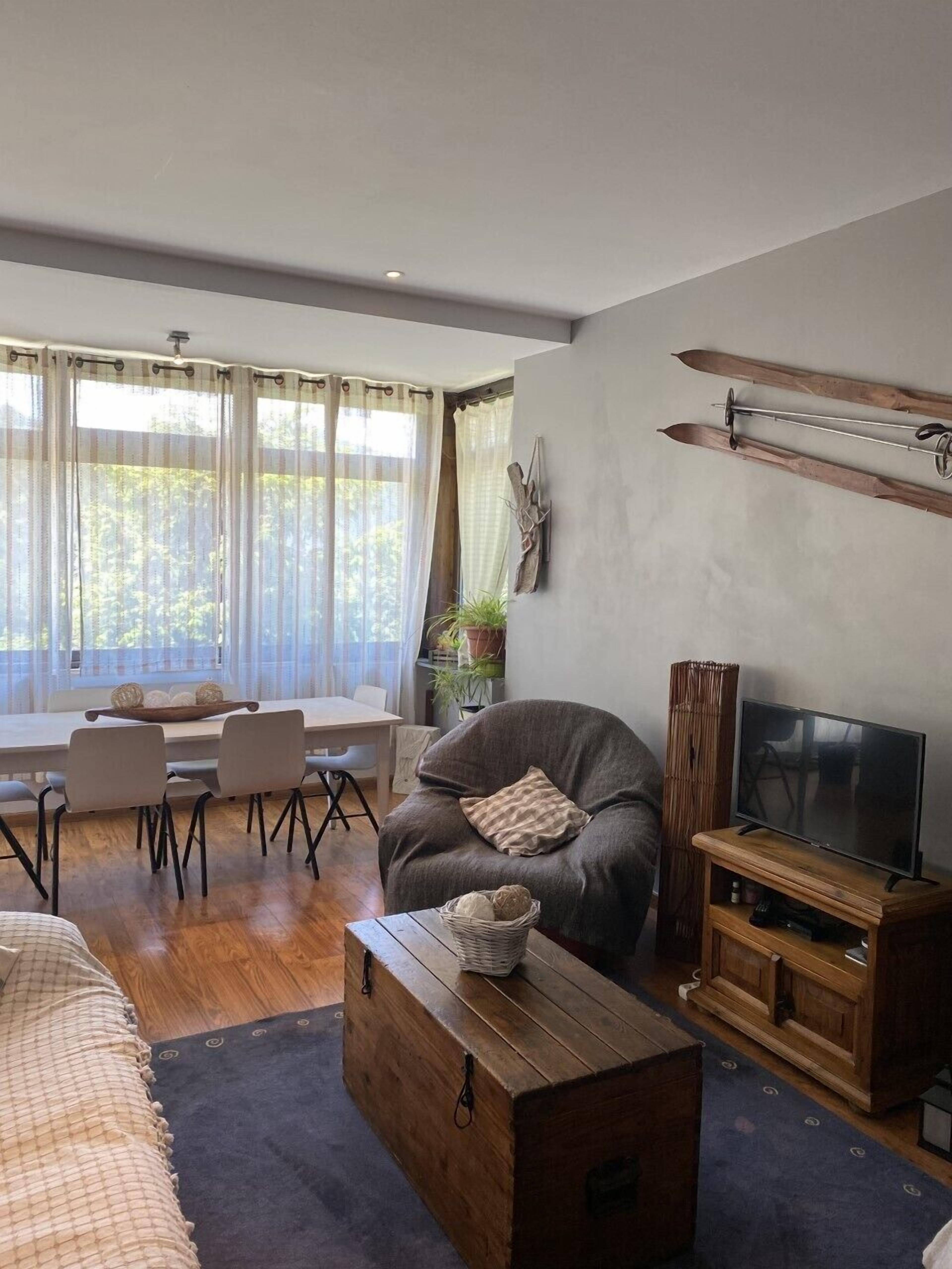Una sala de estar moderna con sofá, mueble para televisión y comedor.