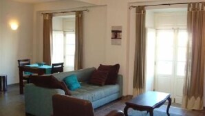 A living room with a sofa, a coffee table, and a dining table. - River view apartment in historical centre of Tavira with roof terrace & WiFi  (Tavira)