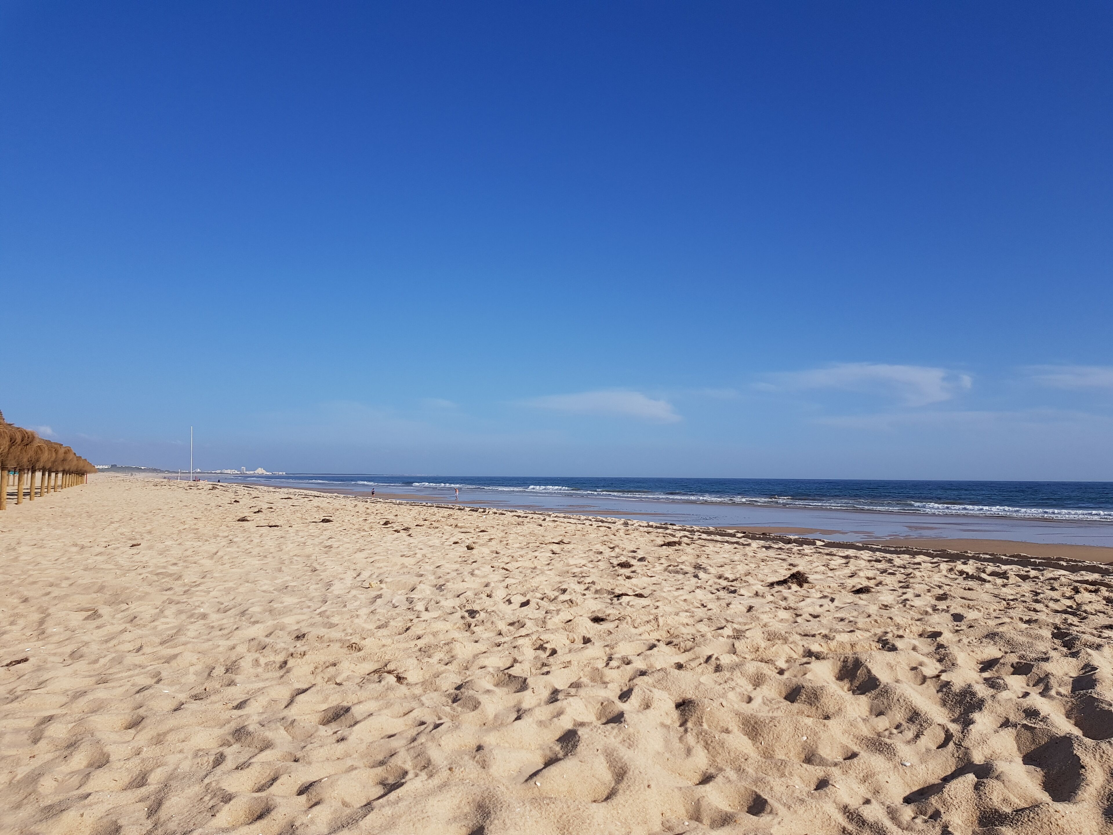 Ein weiter Sandstrand mit blauem, klarem Himmel.