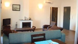 A living room with a sofa, a small table, a fireplace, and a TV. - River view apartment in historical centre of Tavira with roof terrace & WiFi  (Tavira)