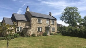 A stone house with a gabled roof, a front door, and a small front yard. - Cosy cottage with large garden in gorgeous rural setting. (Dalwood, Devon)