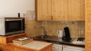 Une cuisine avec des meubles de rangement en bois, un four à micro-ondes, un évier et une machine à café.