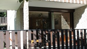 Un balcon avec une balustrade en bois, une fenêtre et une vue sur l’intérieur d’un bâtiment.