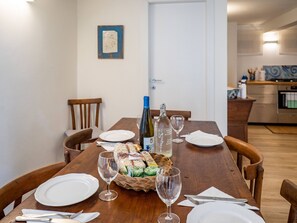 A dining table set with plates, cutlery, wine glasses, and a basket of food.