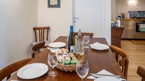 Una mesa de comedor dispuesta con platos, copas de vino, una cesta de pan y una botella de vino.
