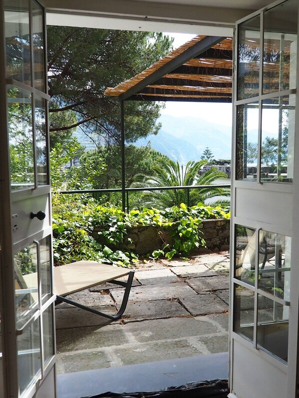 An open door leading to a patio with a view of trees and mountains.